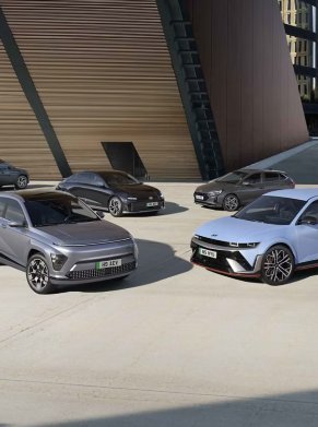 Five modern cars parked on a concrete surface in front of a building.