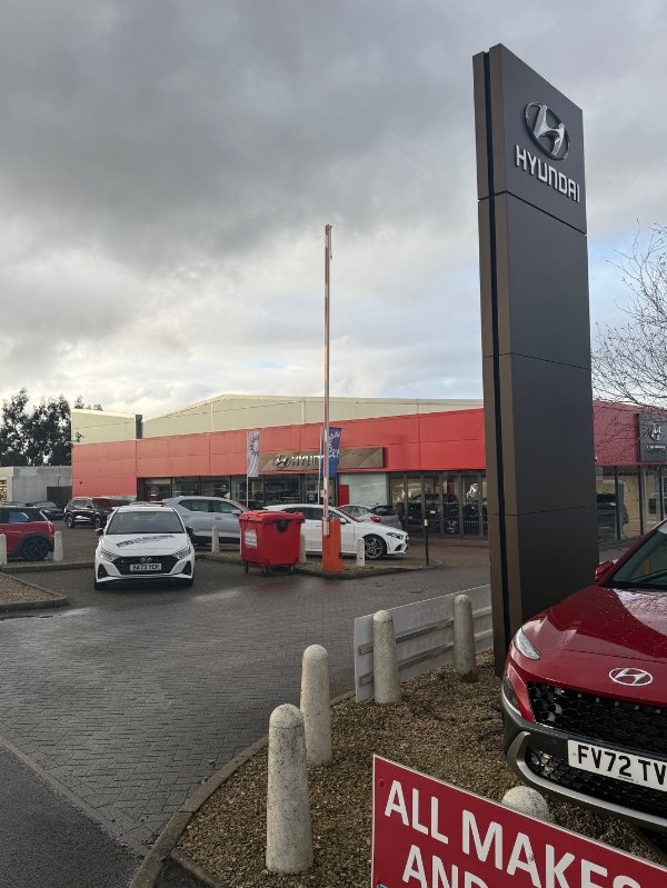 Hyundai dealership lot with several cars and a tall Hyundai sign.
