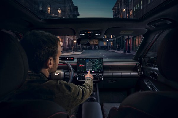 Man using touchscreen navigation system in car interior at night.