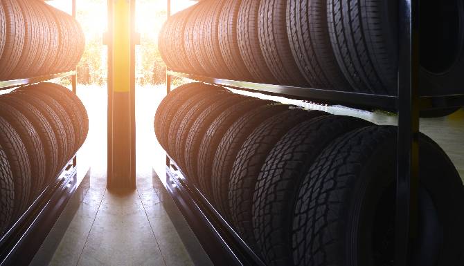 Racks of car tyres in a warehouse with sunlight streaming through.